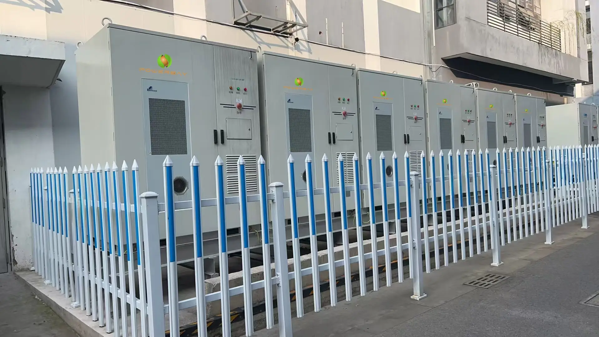 Large format BESS featuring a row of white and blue metal storage units arranged in a neat formation.